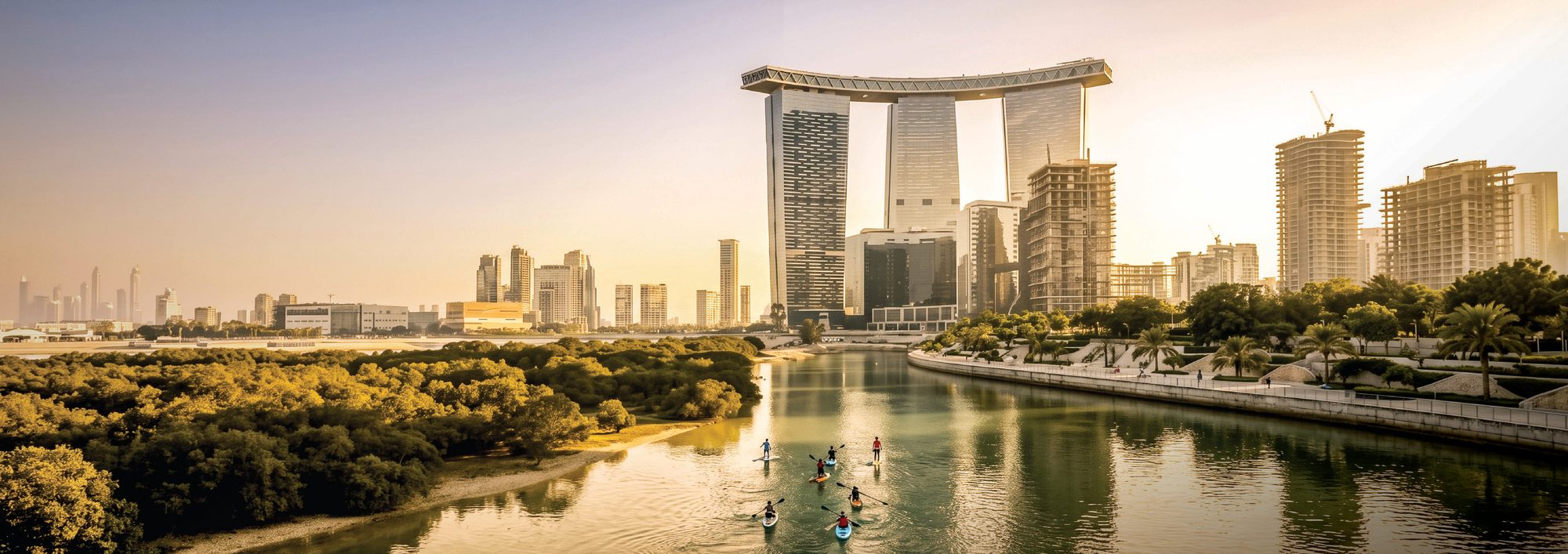 Paddleboarders on a mangrove-lined canal on Al Reem Island at sunset, with Gate Towers behind