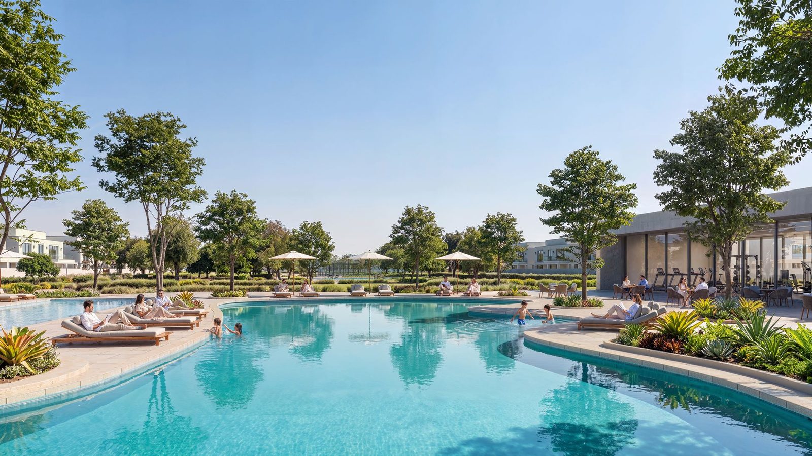 A clubhouse at Wadeem Gardens: a lagoon-shaped pool with loungers, mature trees and a glazed gym pavilion behind